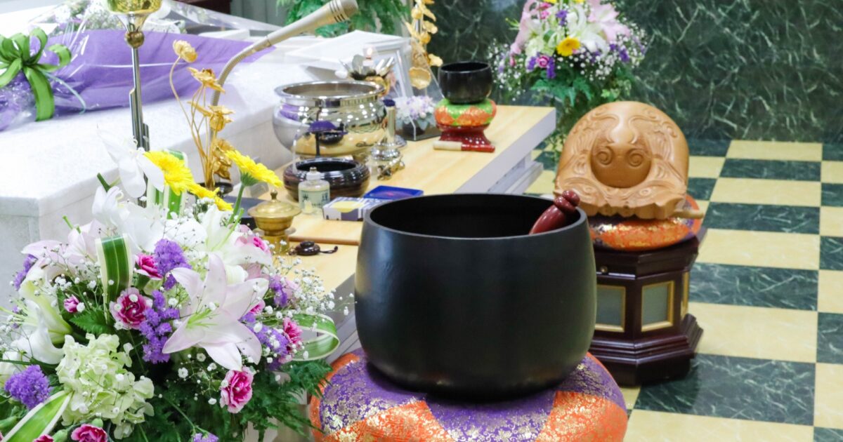 黒いリンが座布団の上に置かれた祭壇の供物と共に飾られた葬儀の風景