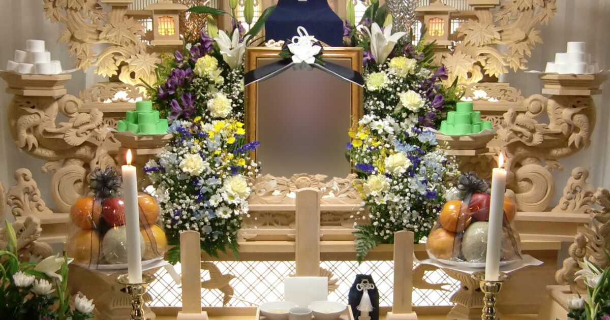 伝統的な木彫りの祭壇に供えられた遺影と供花